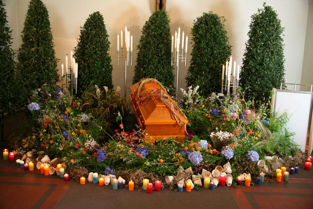 Sarg geschmückt mit bunten Pflanzen und Kerzen - Bestattungsinstitut Schmidt-Peil