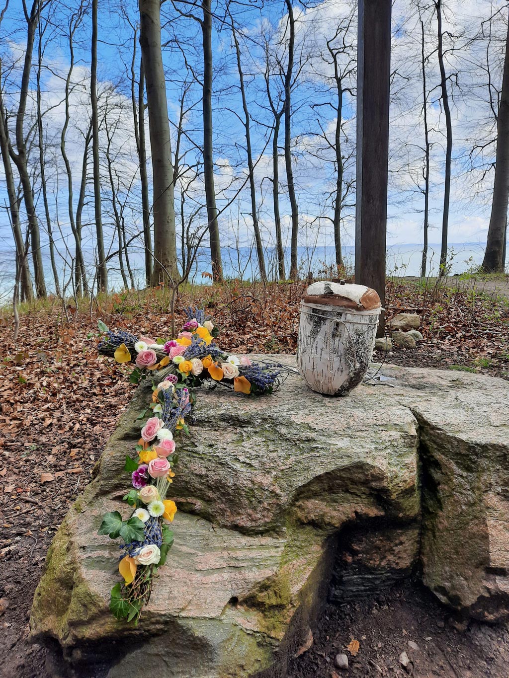 Urne und Kreuz mit Blumen im Wald - Bestattungsinstitut Schmidt-Peil